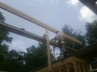 Carpenter setting a ridge beam over a new addition frame — Ice Dam Removal by Roofing Brothers in Central
