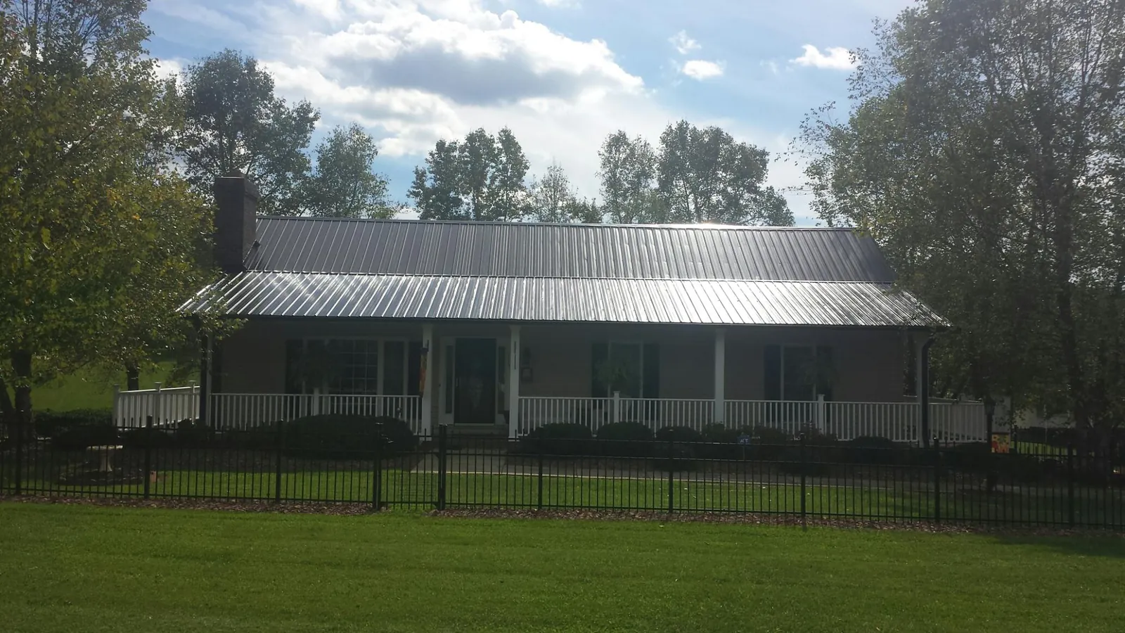 Gray metal roof on a brick ranch with a full width front porch — Gutter Guard Installation work by our crew in Central